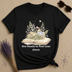 She Reads to Feel Less Alone — Open Book Garden T-Shirt for Women in Black