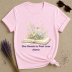 She Reads to Feel Less Alone — Open Book Garden T-Shirt for Women in Light Pink